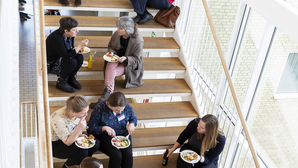 Alumner der sidder på trappen og spiser tapas