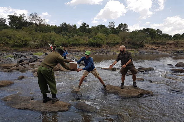 Forskere fra BIOCHANGE og et lokalt ranger team krydser Mara-floden i Maasai Mara i Kenya under feltarbejde i 2018